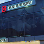 Detailaufnahme der Glasfassade eines Breuninger-Gebäudes mit rotem „B“-Logo und weißem Schriftzug „breuninger“ oberhalb der Schaufenster.