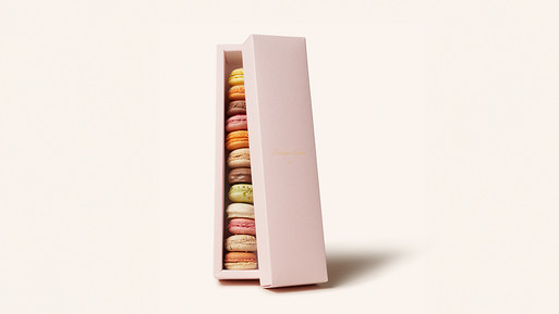 Eine elegante, rosafarbene Macaron Geschenkbox, leicht geöffnet, die eine Auswahl feinster Macarons aus der Breuninger Confiserie offenbart. Die Macarons sind sorgfältig arrangiert und bestechen durch ihre vielfältigen Farben, die pure Genussmomente versprechen. Ein perfektes Geschenk voller Raffinesse und Qualität.