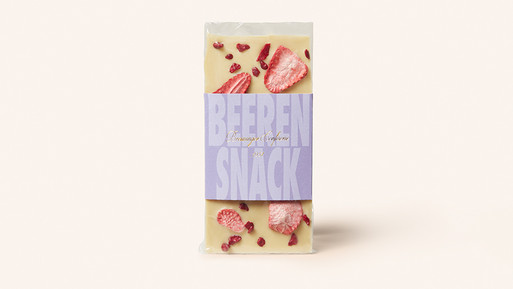 Weiße Schokoladentafel mit gefriergetrockneten Beeren und Papierbanderole auf hellem Hintergrund.