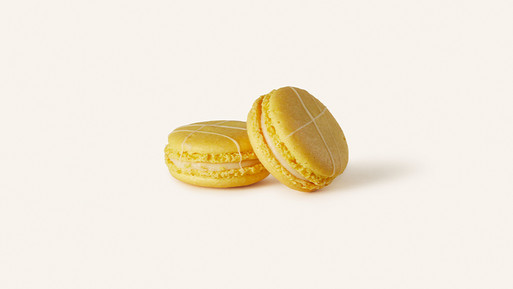 Zwei gelbe Macarons mit Cremefüllung auf hellem Hintergrund.