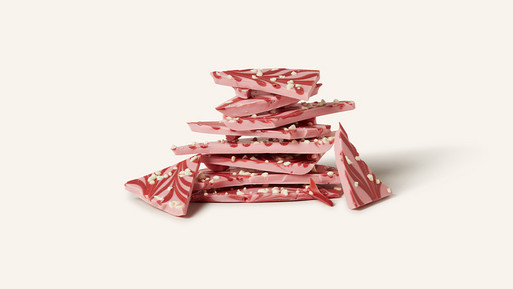 Gestapelte Bruchstücke rosa Schokolade mit dekorativem Muster auf hellem Hintergrund.