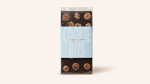 Schokoladentafel mit Keksstücken und Papierbanderole auf hellem Hintergrund.