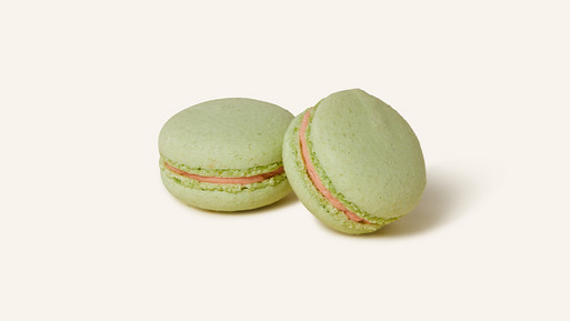 Zwei Rhabarber-Macarons mit einer zart-grünen Schale, gefüllt mit einer roten, fruchtigen Rhabarber-Ganache. Die feine Säure des Rhabarbers trifft auf süße Eleganz – ein erfrischender Genuss aus der Breuninger Confiserie.