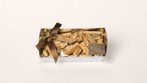 Gedanken Gedanken in die Zwischenablage kopieren Längliche Käsegebäckstücke mit Sesam und Mohn bestreut, liebevoll in einer silbernen Schachtel mit brauner Schleife verpackt – herzhafte Leckerbissen mit aromatischem Aroma, perfekt als Geschenkidee aus der Breuninger Confiserie.