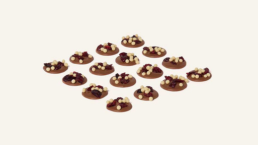 Viele kleine, runde Palets au Chocolat mit feinem Topping in Rasteranordnung auf hellem Hintergrund – feine, französische Schokoladenplätzchen aus der Breuninger Confiserie.
