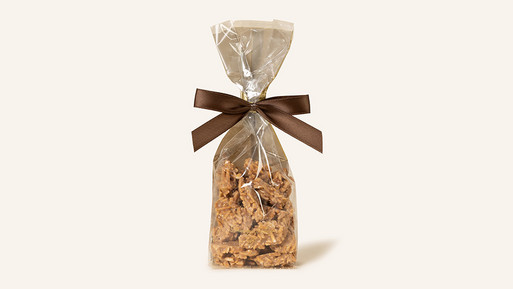 Beutel mit Krokantstücken, verpackt in transparenter Folie mit Schleife.