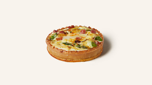 Herzhafte Quiche mit Gemüse und Käse auf hellem Hintergrund.