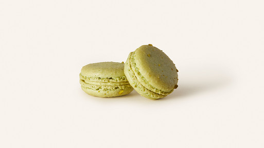 Zwei grüne Macarons mit Cremefüllung auf hellem Hintergrund.