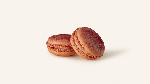 Zwei braunrosafarbene Macarons mit Cremefüllung auf hellem Hintergrund.