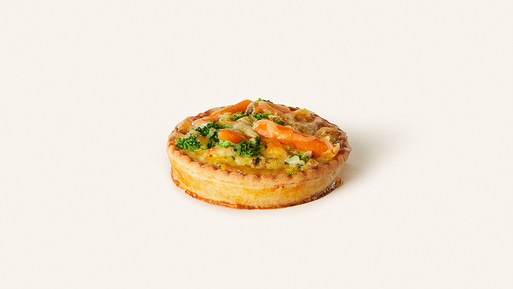 Herzhafte Quiche mit Gemüse und Käse auf hellem Hintergrund.