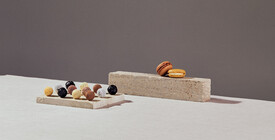 Präsentation von Pralinen und Macarons auf einer Steinplatte und einem Block.