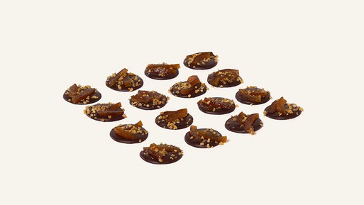 Viele kleine, runde Palets au Chocolat aus Vollmilch-Schokolade mit feinem Topping in Rasteranordnung auf hellem Hintergrund – feine, französische Schokoladenplätzchen aus Zartbitter Schokolade, aus der Breuninger Confiserie.
