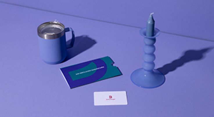 Blaue Kerze, blaue Tasse, Geschenkkarte, lilafarbener Hintergrund.