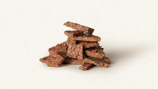 Gestapelte Schokoladenbruchstücke mit Nussanteilen auf hellem Hintergrund.