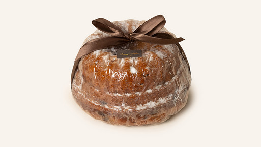 Ein eleganter Gugelhupf, bestäubt mit Puderzucker.  Das Highlight ist die liebevolle Verzierung mit einer edlen, braunen Schleife, die dem Kuchen eine besondere Note verleiht. Ein Meisterwerk aus der "Breuninger Confiserie", das Tradition, Genuss und Stil in Perfektion verbindet.