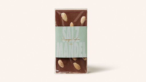 Schokoladentafel mit ganzen Mandeln und Papierbanderole auf hellem Hintergrund.