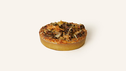 Herzhafte Quiche mit Pilzen und Käse auf hellem Hintergrund.