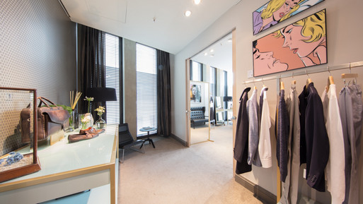 Moderner Showroom mit Kleiderständer, Präsentationstisch, Spiegeln und dekorativer Wandkunst.