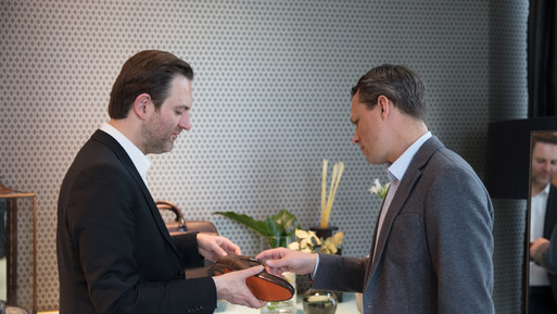 Zwei Männer betrachten gemeinsam ein Paar Schuhe in einem stilvollen Verkaufs- oder Beratungsbereich.