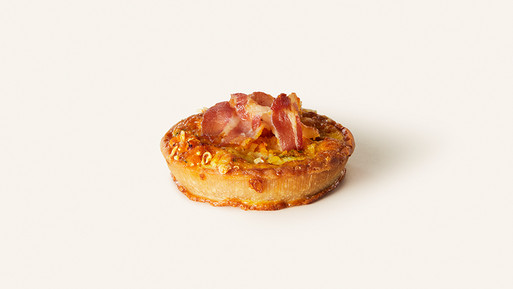 Herzhafte Quiche mit Speck und Käse auf hellem Hintergrund.